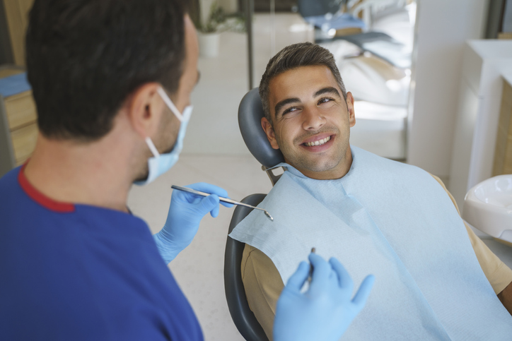 Man smiling in the dentist's chair at his dental hygienist